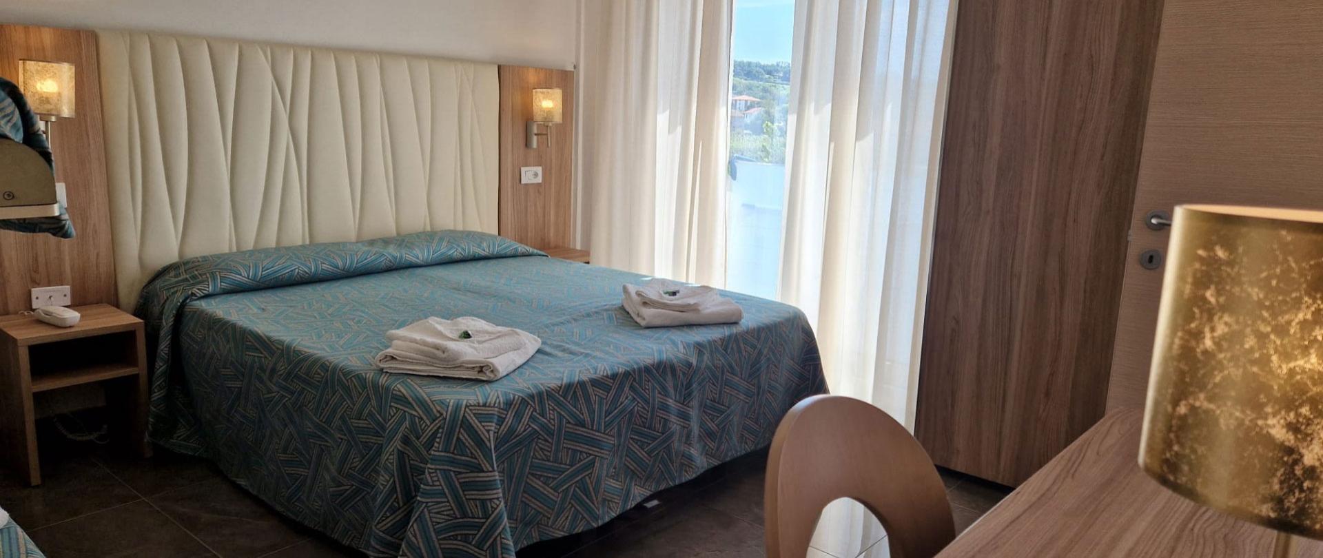 Bright, cozy room with double bed, white curtains, and wooden details.