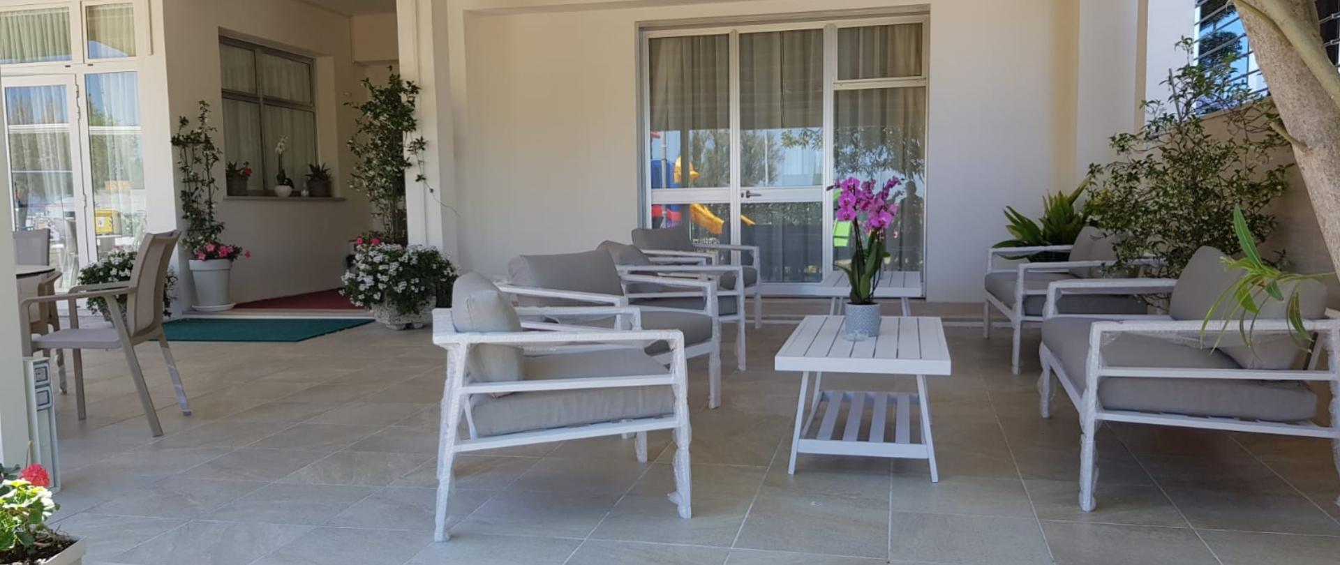 Bright space with comfy chairs, plants, and colorful flowers.