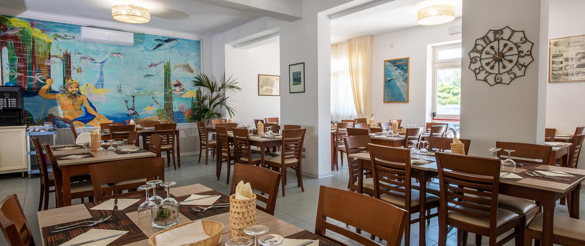 Ristorante accogliente con murale marino e tavoli elegantemente apparecchiati.