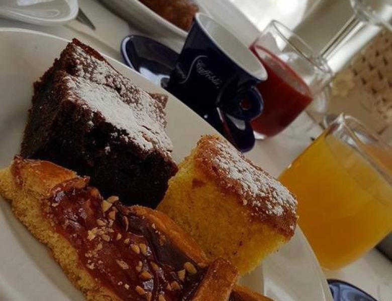 Colazione golosa con dolci, succo e caffè, avvolta da luce calda.