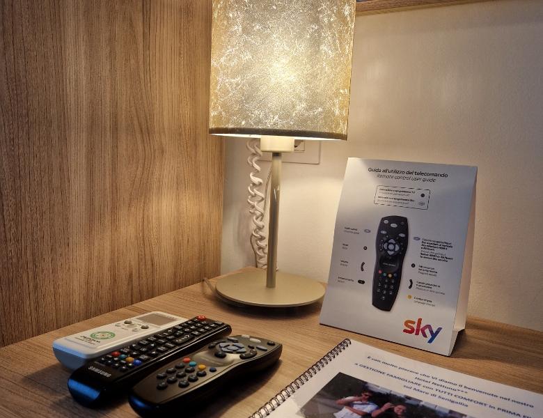 A lit lamp illuminates remotes and Sky guide on a cozy table.