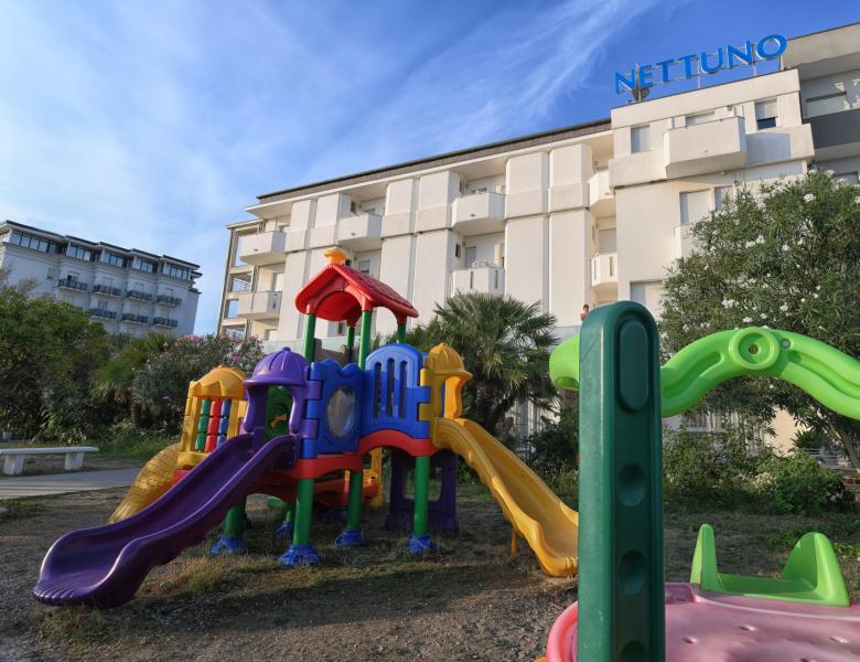 Parco giochi colorato davanti a un hotel, cielo sereno e atmosfera gioiosa.