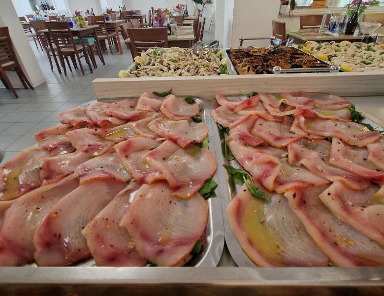 Affettati di pesce crudo su vassoi, conditi con olio, in un ristorante elegante.