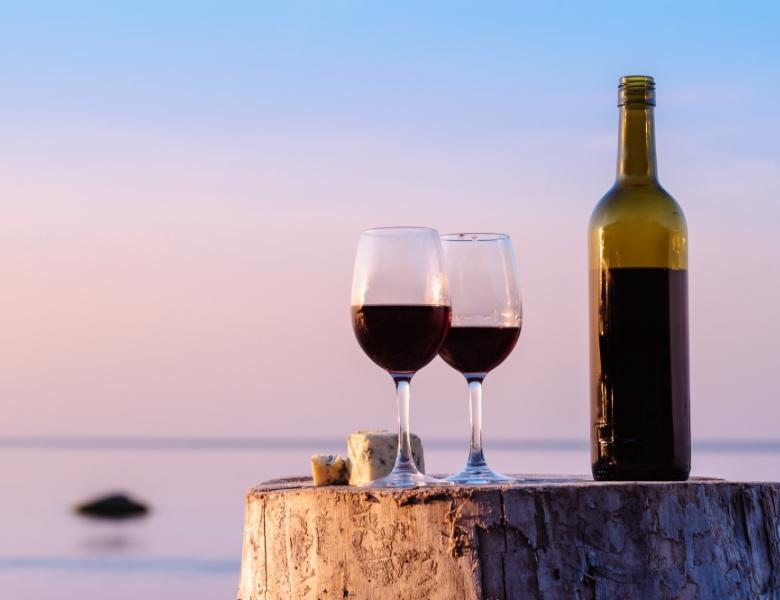 Sonnenuntergang, Rotwein und Käse auf Baumstumpf, romantische und ruhige Stimmung.