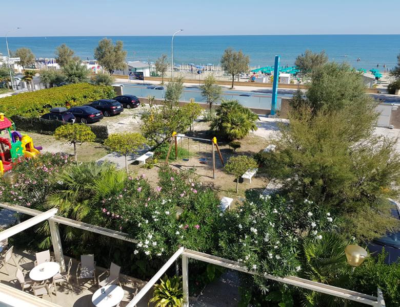 Vista mare con giardino, giochi colorati e relax estivo.